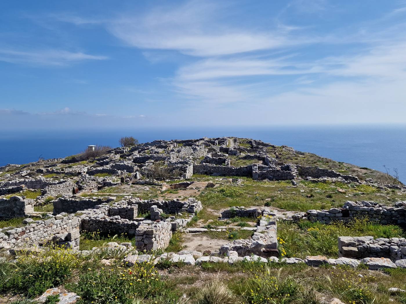 Stone ruins of Ancient Thera stretching along the clifftop ridge of Mesa Vouno, with the sea visible on either side