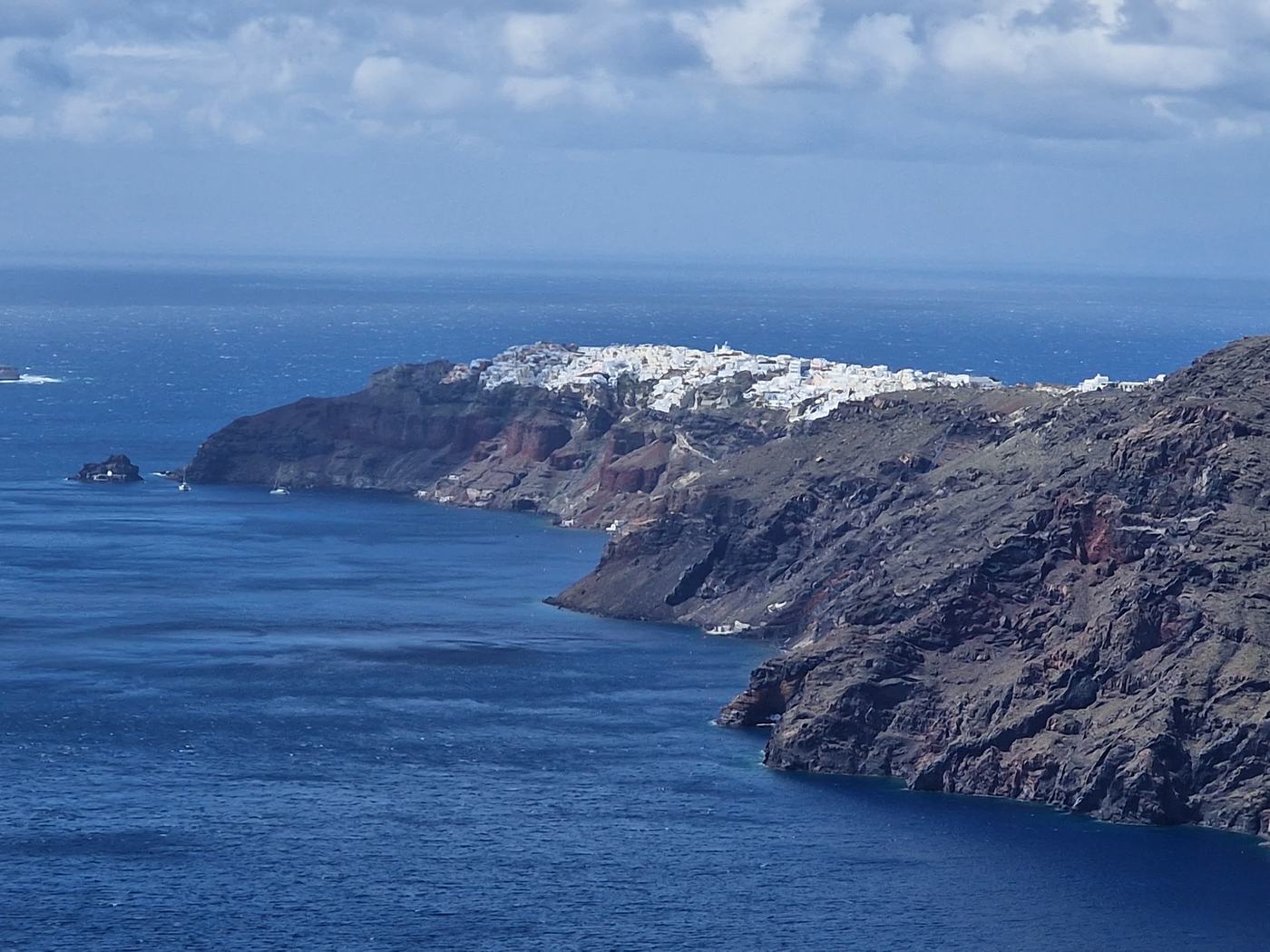 The caldera-rim trail winding along the cliffs, with Oia visible in the distance ahead