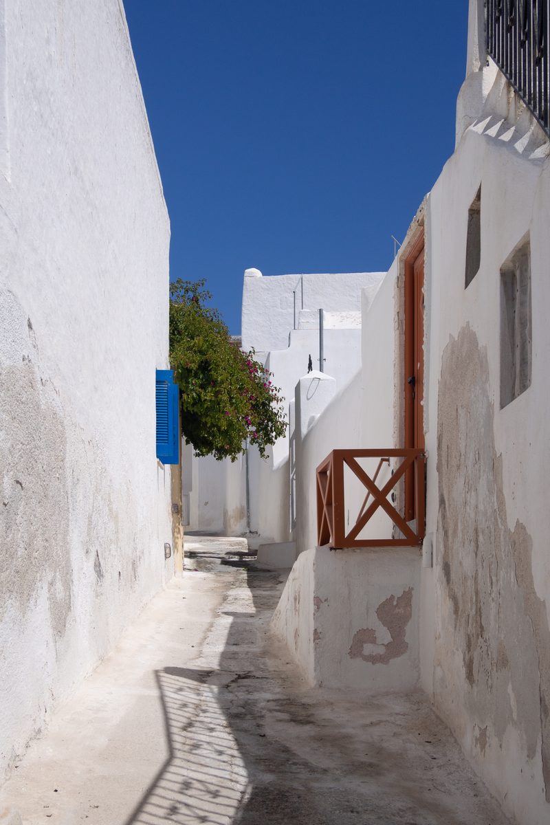 A narrow street lined with whitewashed buildings in Emporio Village, Santorini.