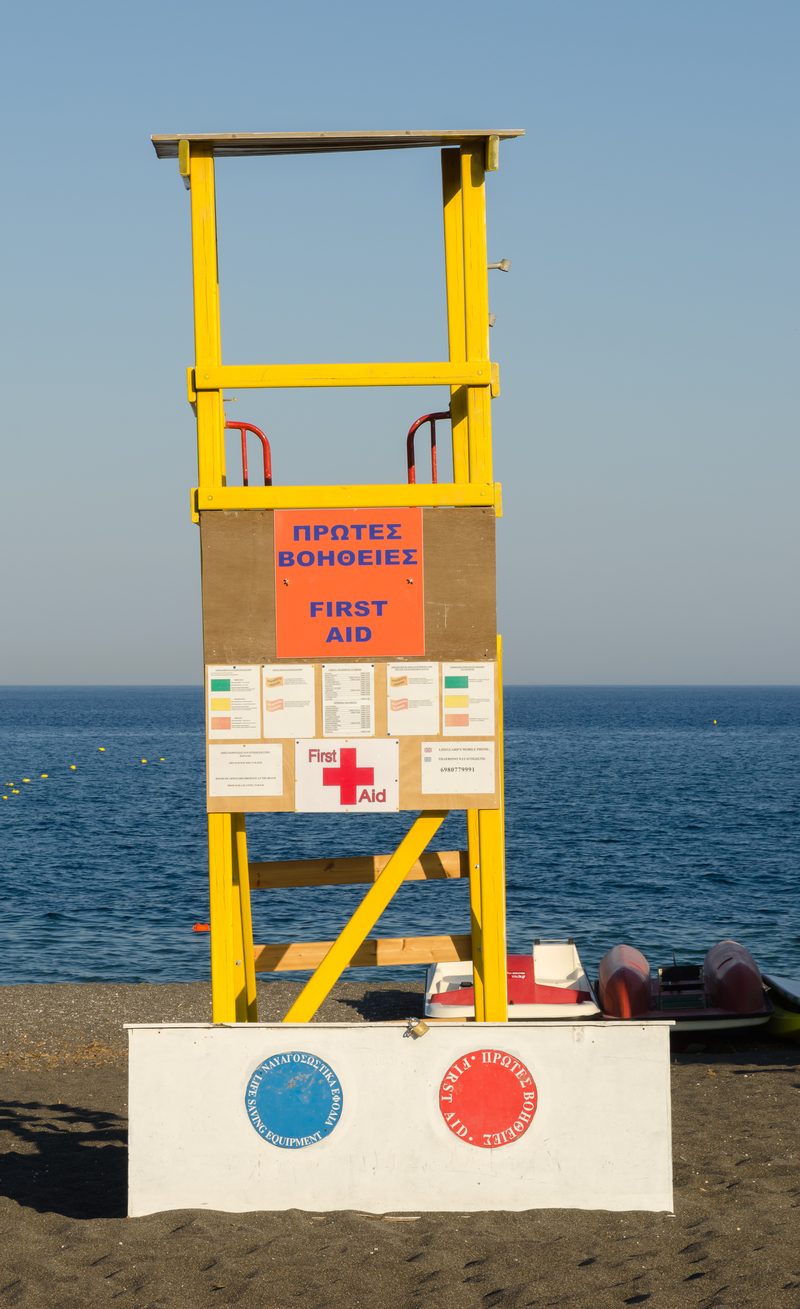 A lifeguard stands on duty at Perissa Black Sand Beach in Santorini, Greece.