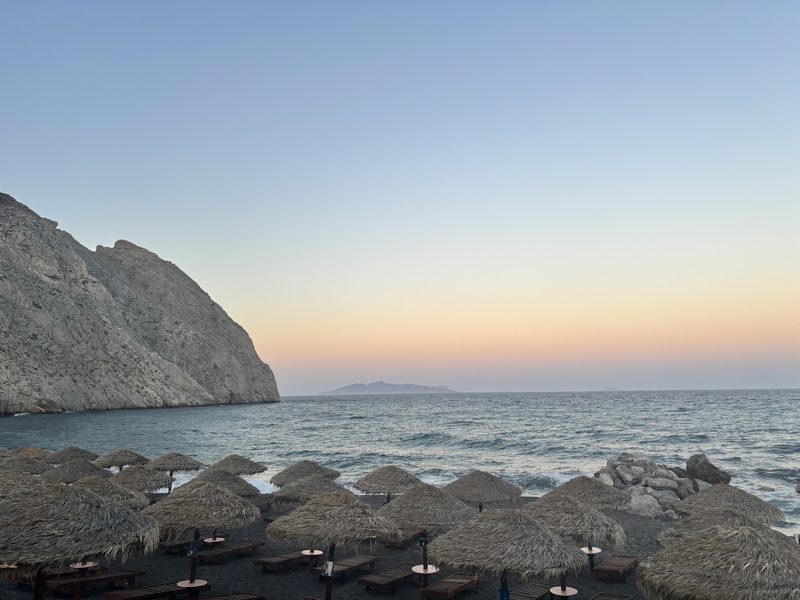A serene view of Perissa Beach with Mésa Vounó in the background, Perissa, Santorini, Greece.