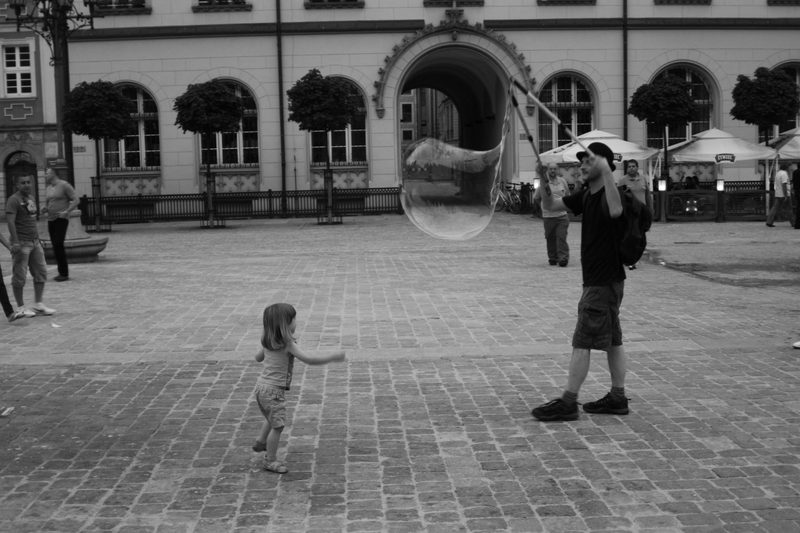 A child joyfully plays with soap bubbles in a picturesque setting in Santorini.