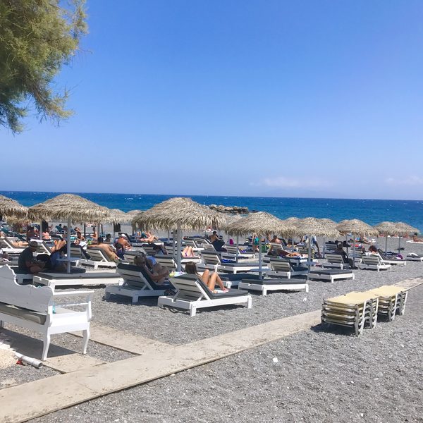 Kamari's black sand beach with clear turquoise water, Santorini