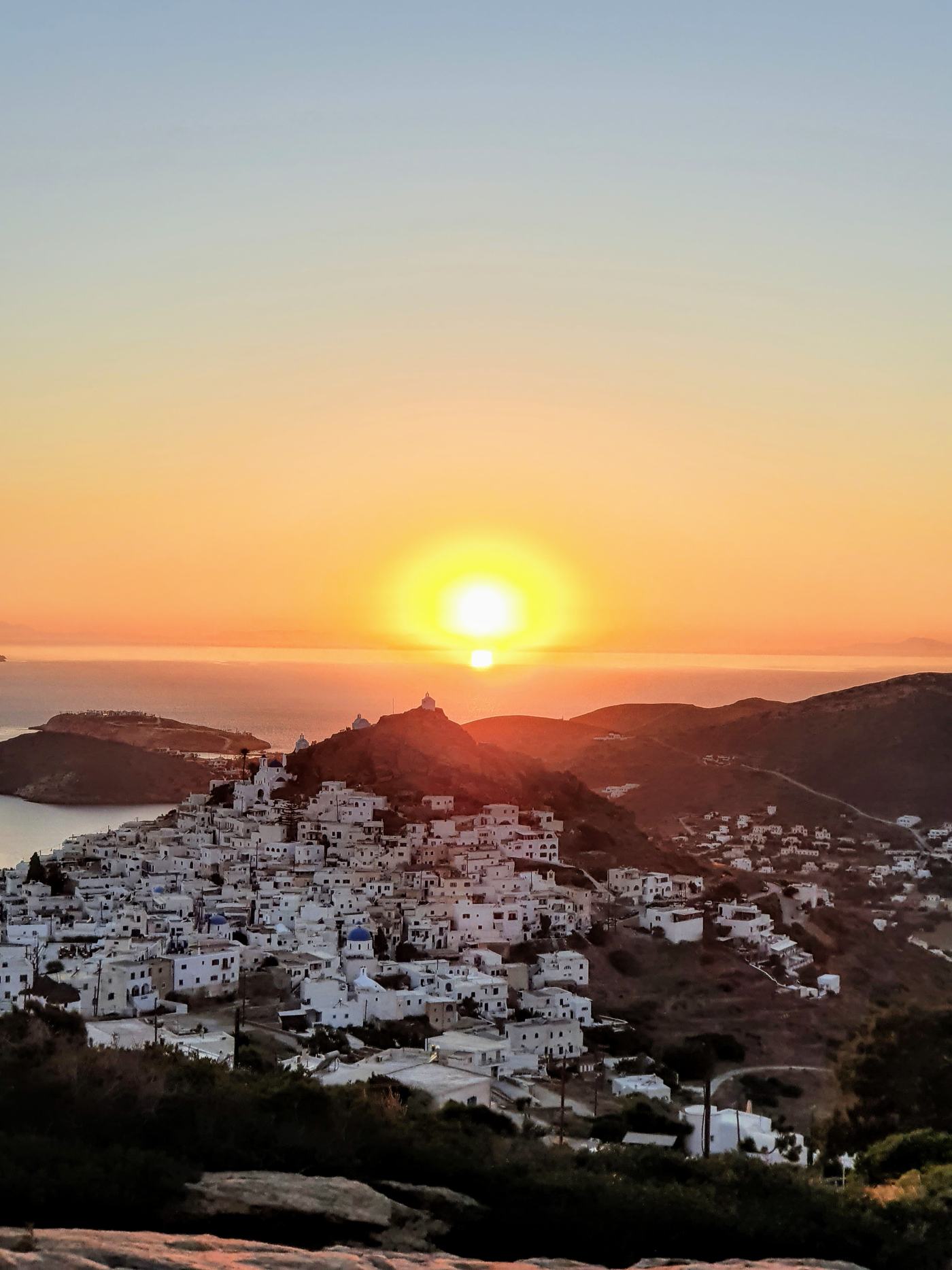 Sunset over the whitewashed hilltop village of Ios Chora with a windmill silhouette